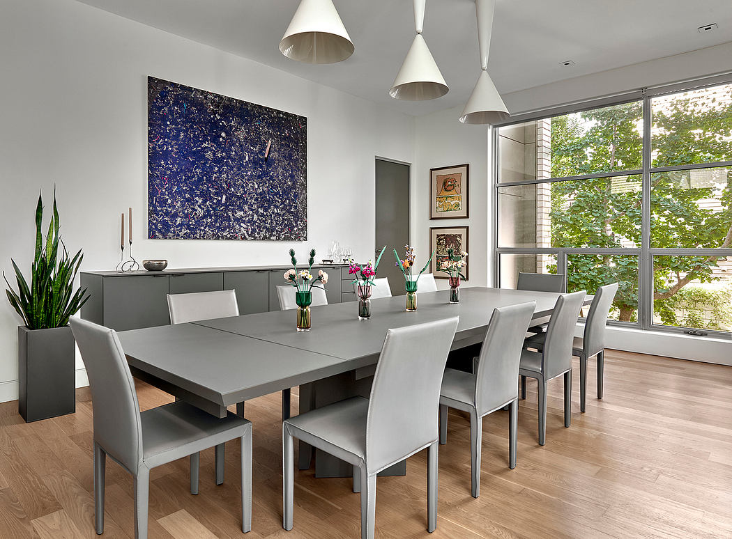 Sleek, modern dining room with large abstract art, statement light fixtures, and lush greenery.
