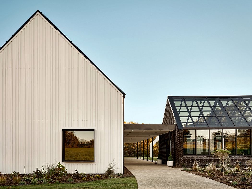 Modern farmhouse-style building with sleek glass atrium and landscaped grounds.