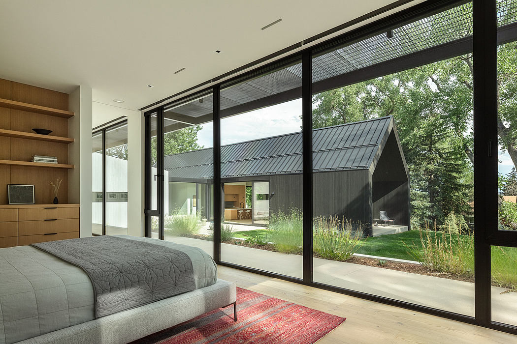 Spacious bedroom with expansive windows overlooking lush outdoor landscape.