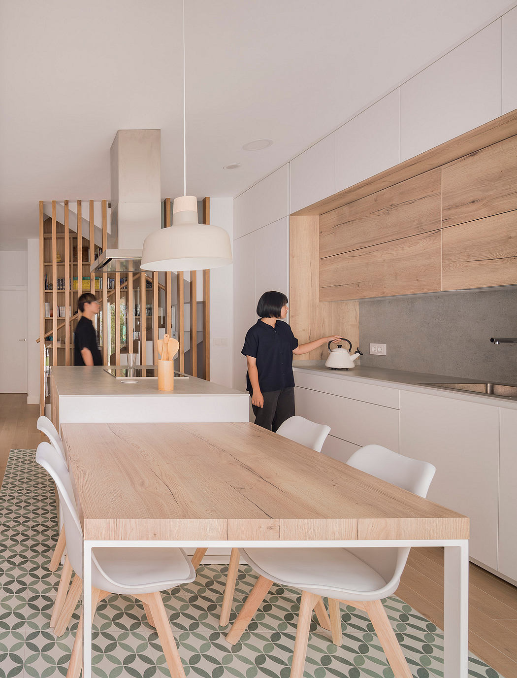 Minimal, modern kitchen with wooden cabinetry, marble backsplash, and patterned tile flooring.