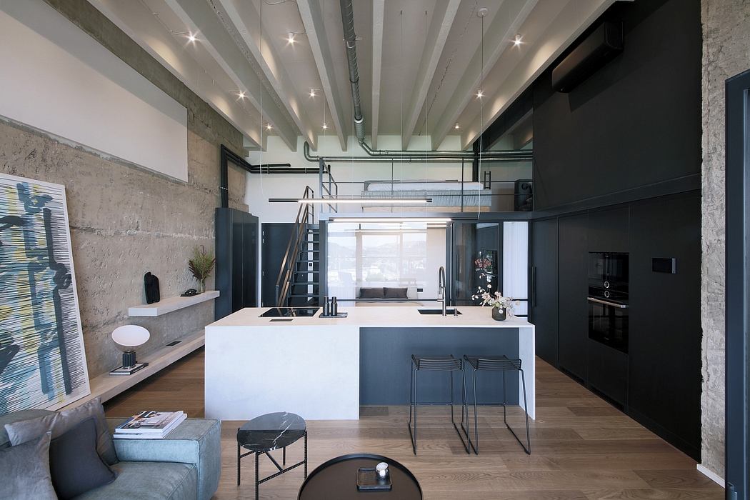 A modern, open-concept kitchen and living area with industrial-style exposed beams.
