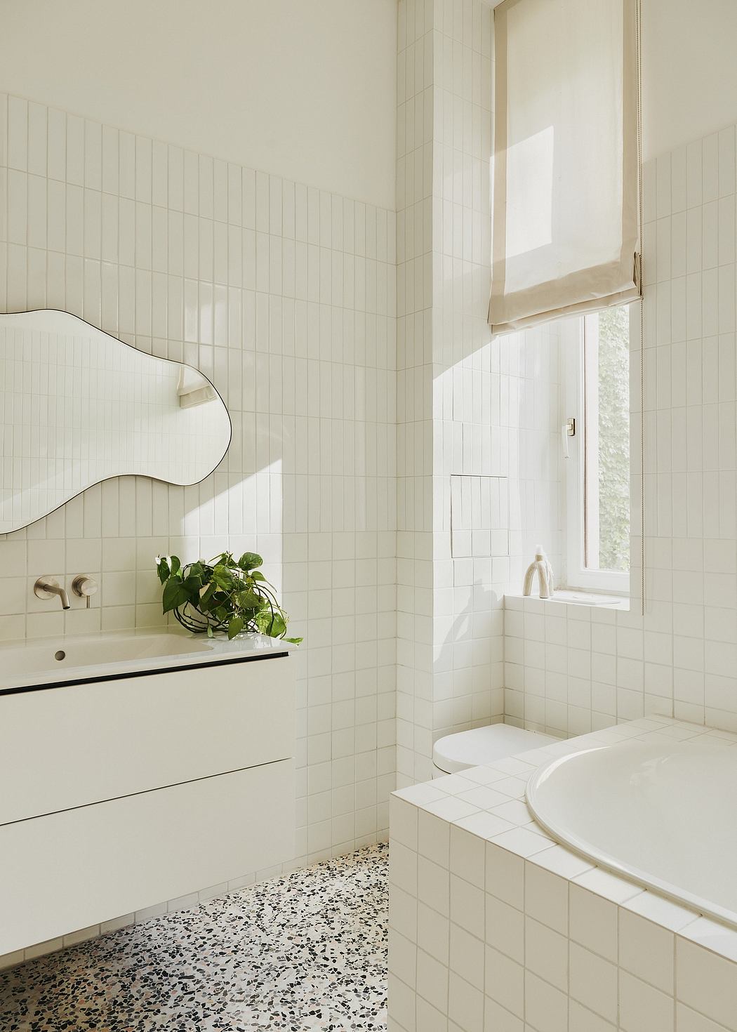 Minimalist bathroom design with rectilinear tiles, terrazzo flooring, and natural lighting.