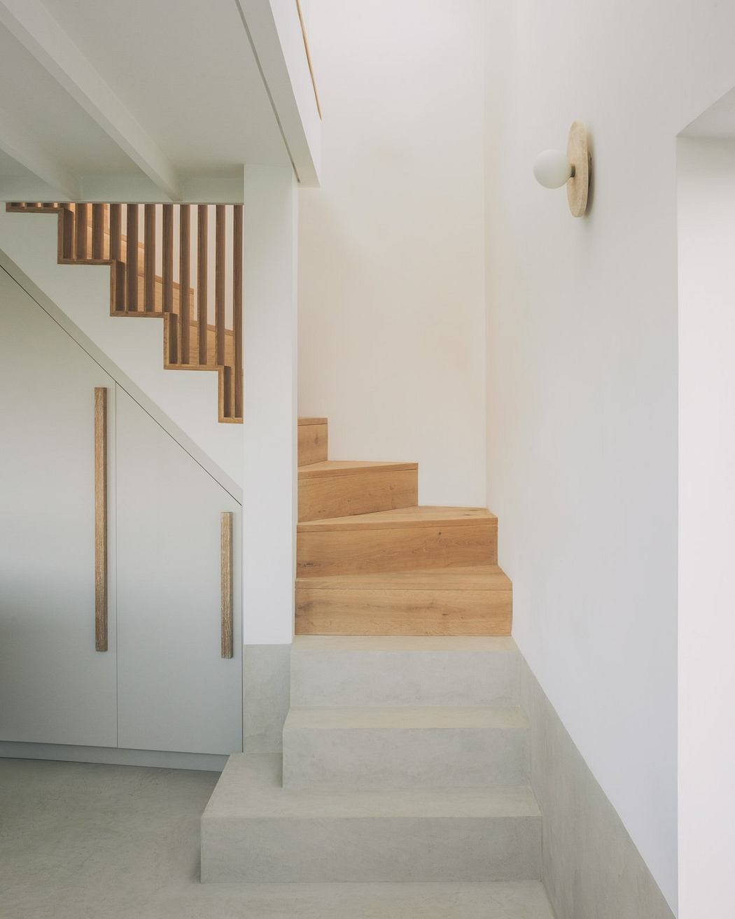 Sleek modern staircase with wooden steps and railing, accented by minimalist decor.