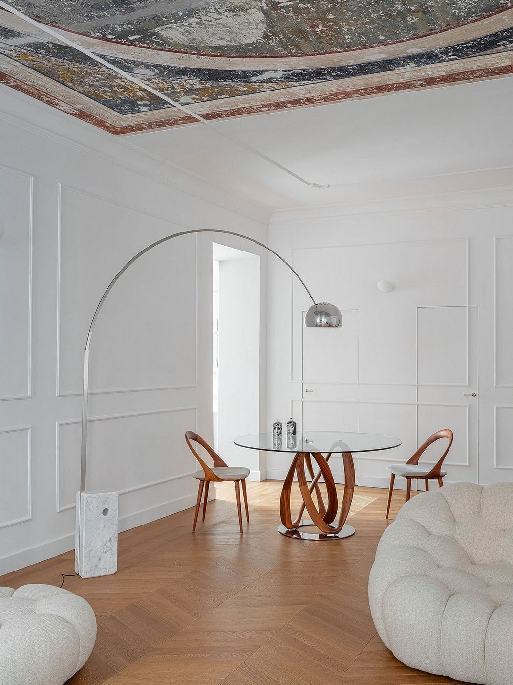 Elegant interior with intricate ceiling design, glass-topped table, and curved wood chairs.