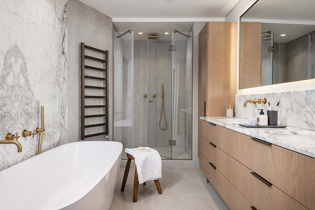 Luxurious bathroom with marble walls, freestanding tub, glass shower, and wooden vanity.