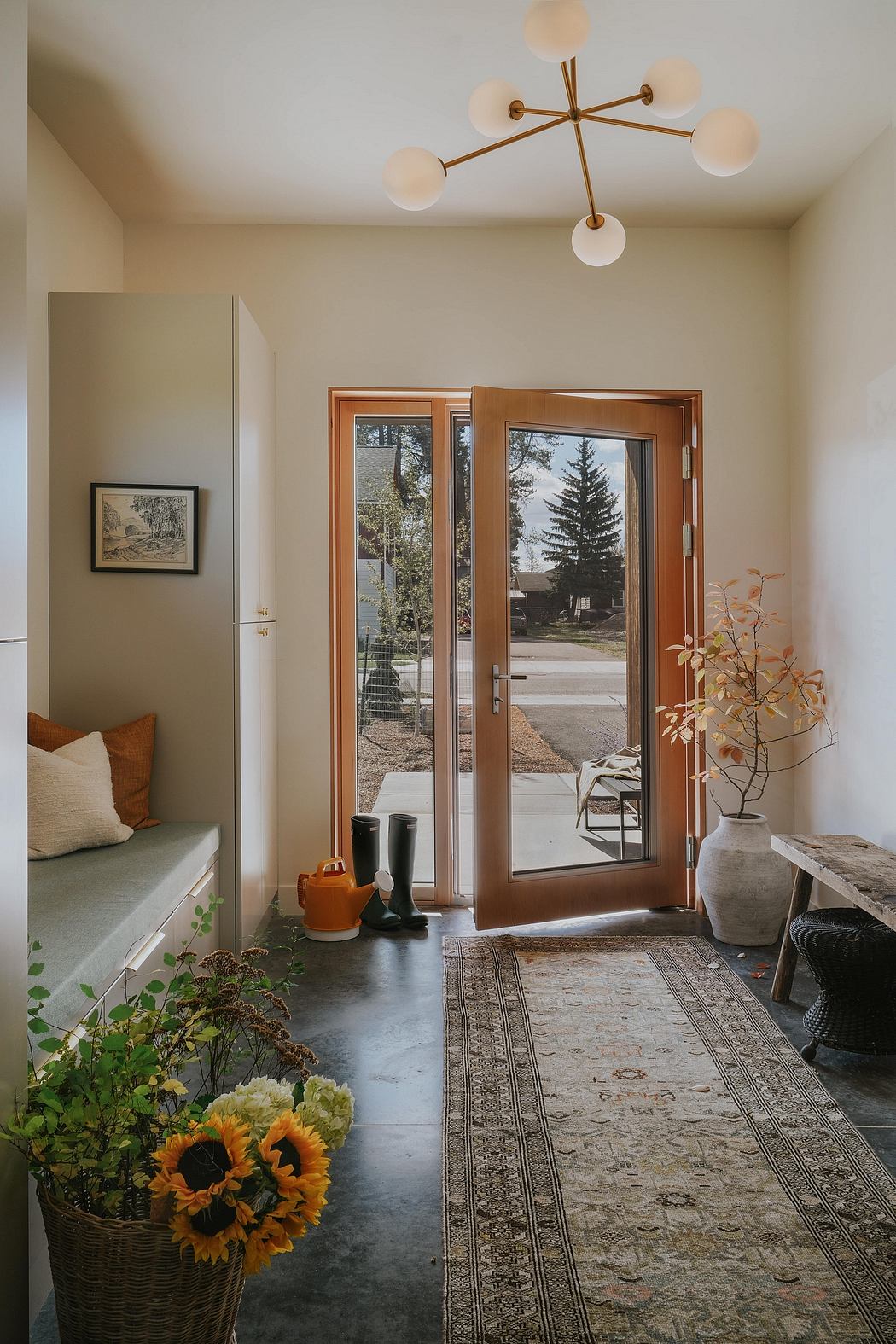 Warm, modern entryway with a striking light fixture, wooden doors, and cozy furnishings.