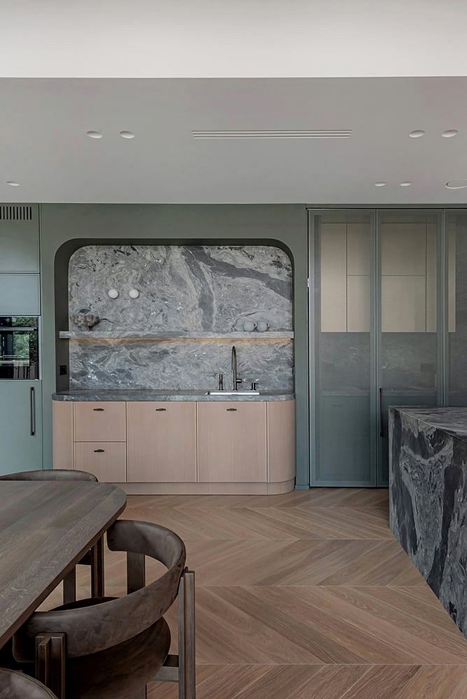 Minimalist kitchen design with marble countertop, neutral tones, and wooden floor tiles.