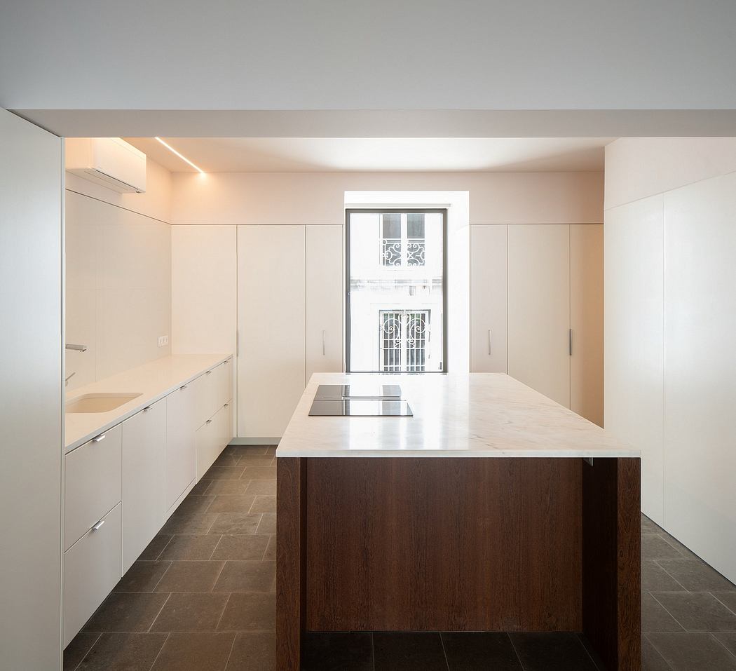 A modern kitchen interior with white cabinets, dark wooden island, and large window.