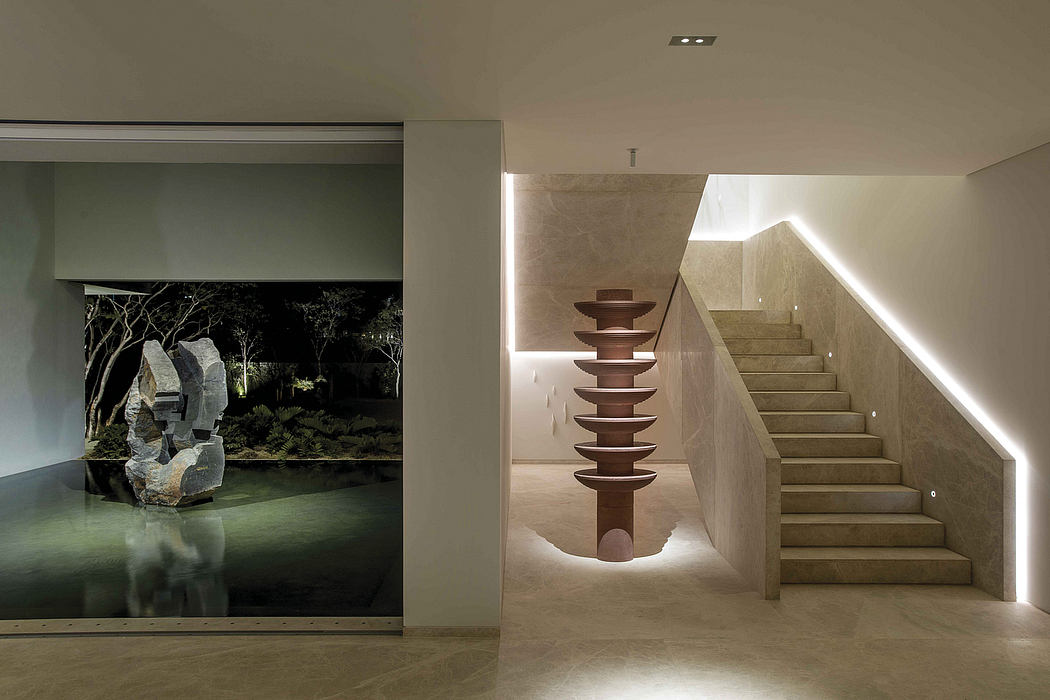 A modern, minimalist staircase with a sculptural column feature, illuminated alcove, and indoor garden.