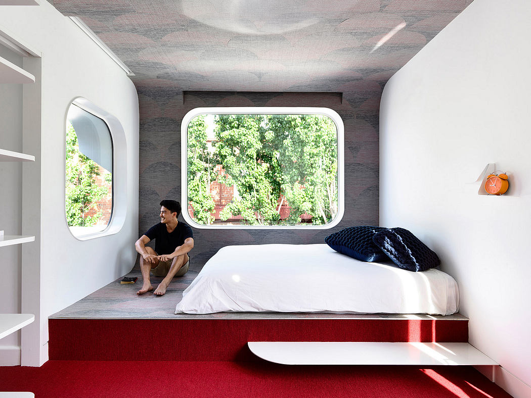 A modern bedroom with a large arched window, minimalist shelving, and a raised platform bed.