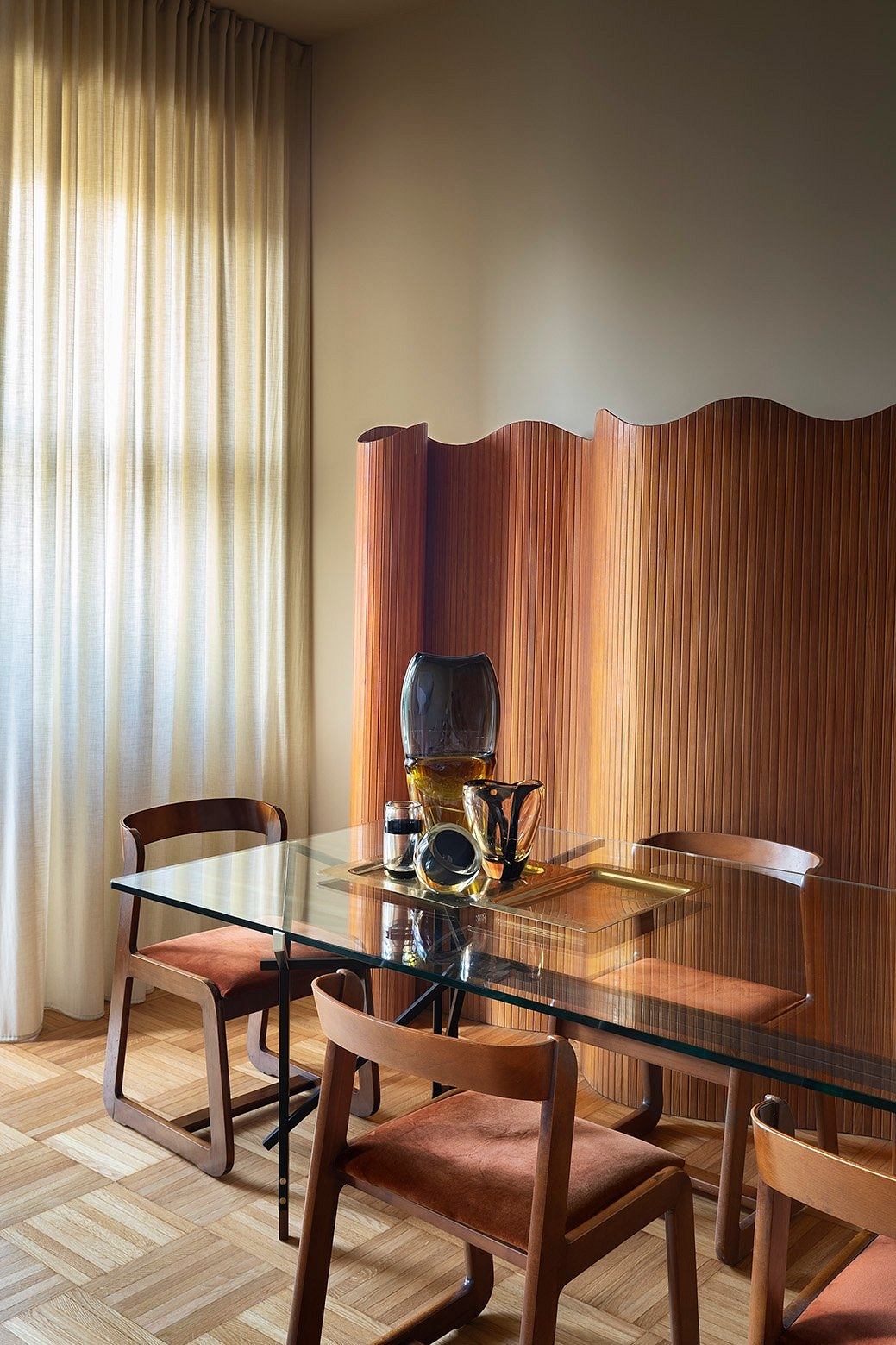 A spacious dining room with a glass table, wooden chairs, and a decorative wooden partition.