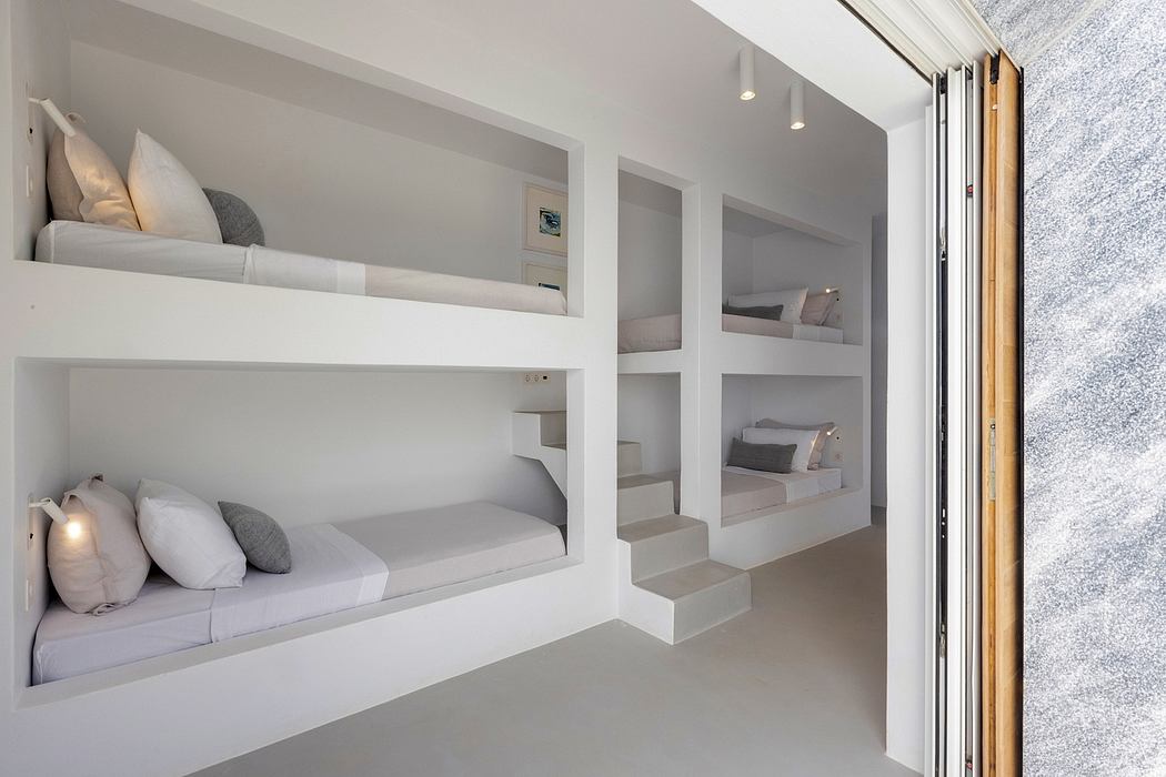 Modern, minimalist bedroom with built-in bunk beds, shelving, and recessed lighting.