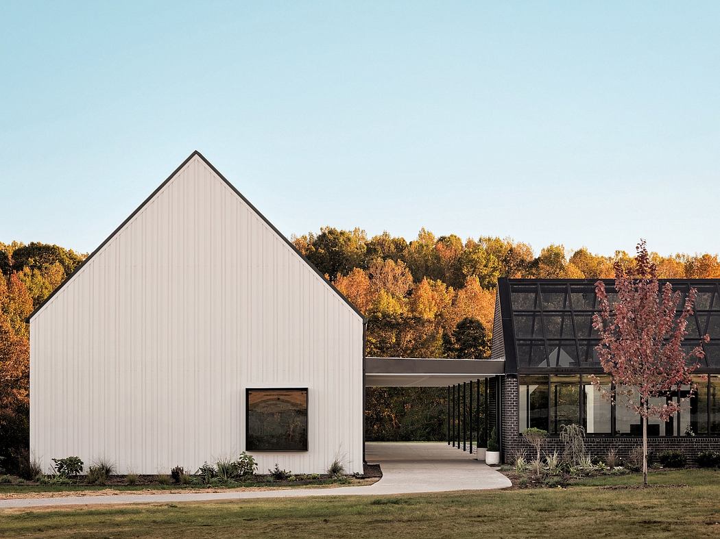 Modern, minimalist building with clean lines, large windows, and a striking roofline against an autumnal landscape.