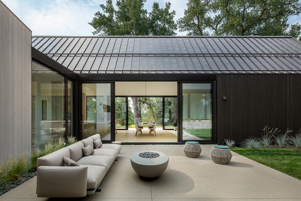 Modern exterior with sleek metal roof, large windows, and minimalist outdoor seating.