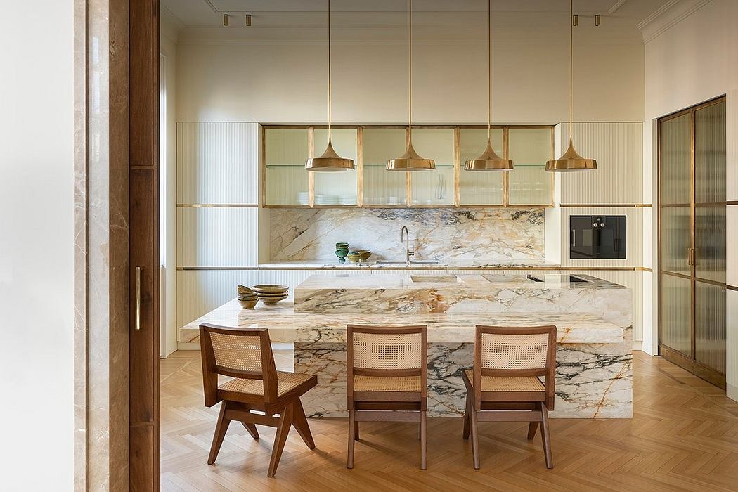 Luxurious modern kitchen with marble countertops, brass lighting, and wood furnishings.