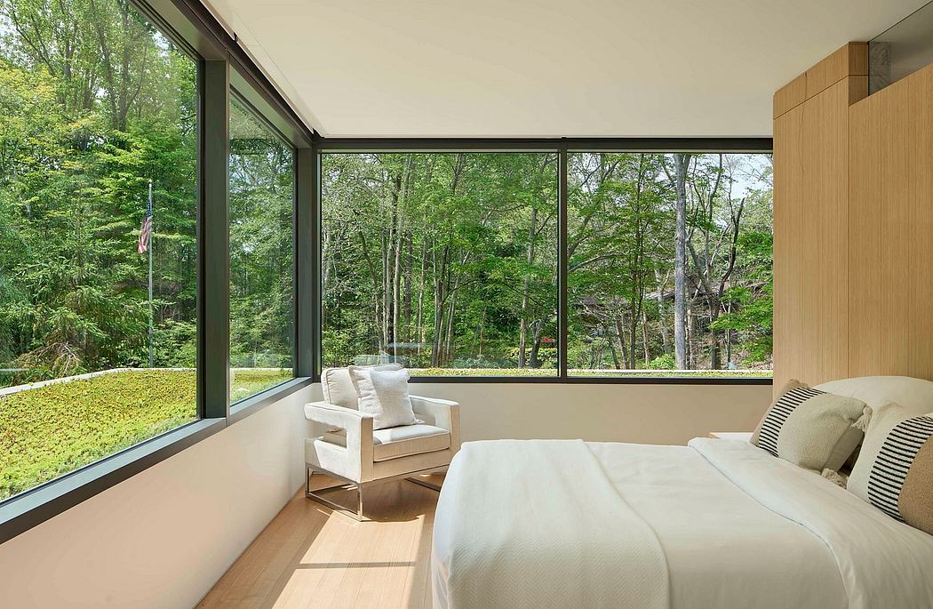 Serene modern bedroom with expansive glass walls overlooking lush greenery.