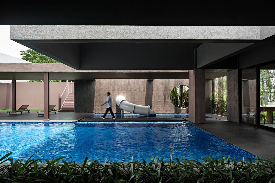 A modern architectural design with a pool, slide, and lush greenery surrounding the space.