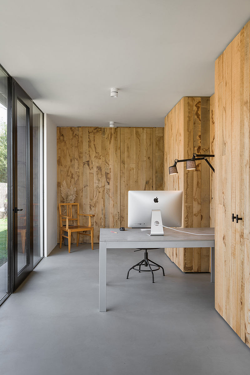 Minimalist office space with rustic wooden walls, modern gray desk, and an iMac.