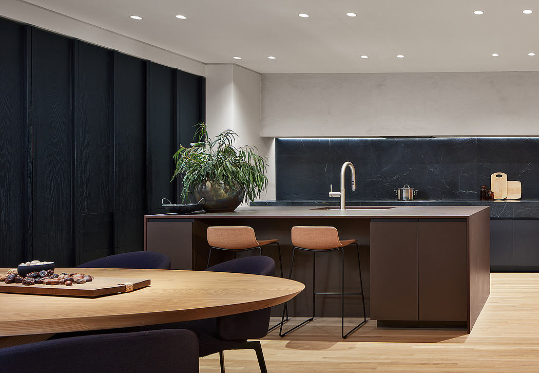 Modern, sleek kitchen with black cabinetry, marble backsplash, and wooden dining table.