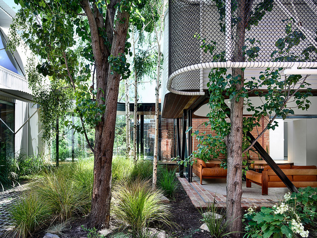 A modern outdoor living space surrounded by lush greenery and a brick facade.