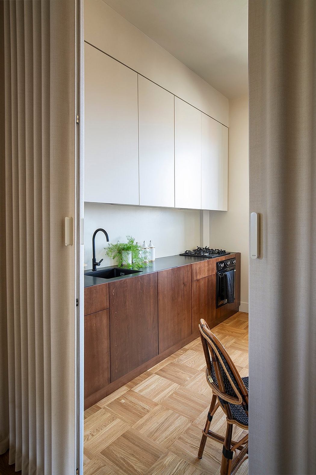 Compact kitchen with modern wood cabinetry, black countertop, and patterned floor.