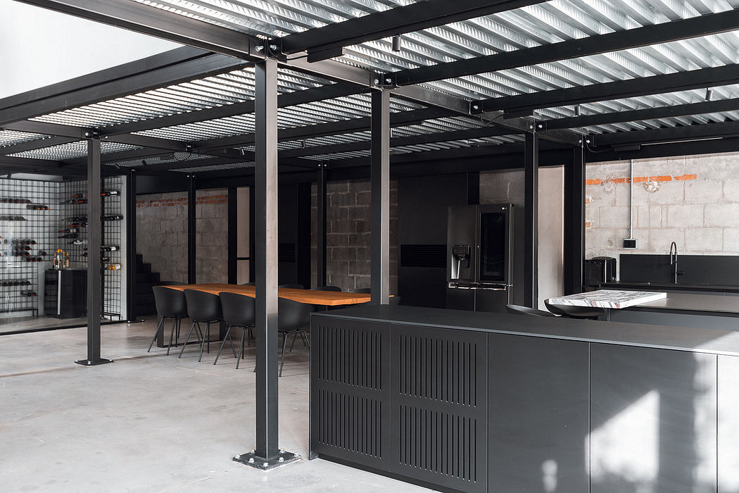 Modern industrial-style interior with black steel beams, gray concrete walls, and sleek kitchen counter.