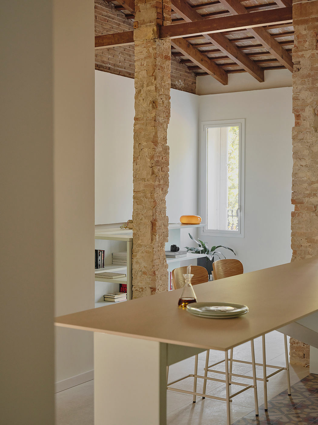 Exposed brick walls, wooden beams, and a minimalist table create a modern rustic aesthetic.