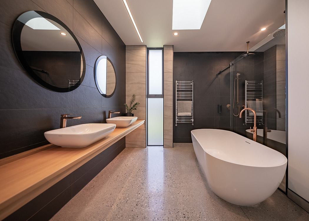 Modern bathroom with sleek, dark tiles, vessel sinks, and a freestanding tub.