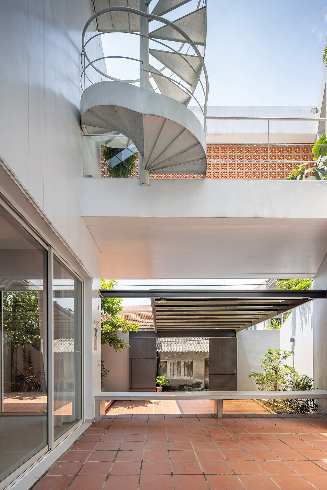Spiral staircase, open-concept layout, and terracotta tiles create a modern, airy space.