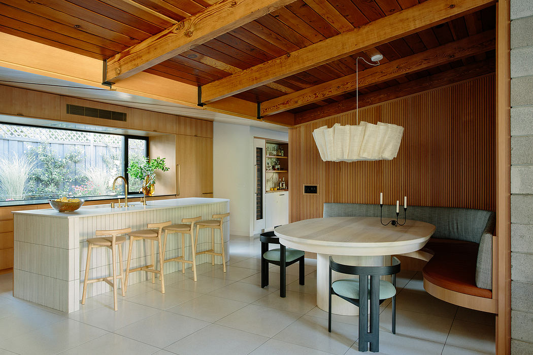 Warm, modern kitchen with wooden beams, sleek island, and a cozy dining nook.