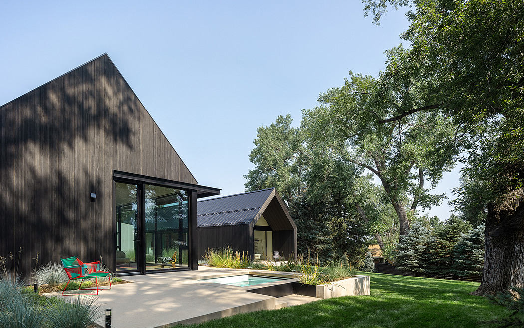 Modern wood-clad home with large glass windows, pool, and lush landscaping.