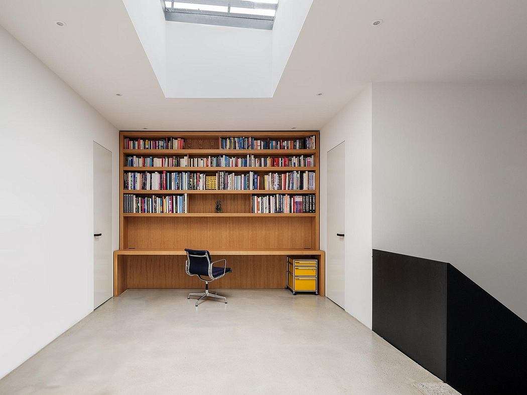 A bright, minimalist home office with a floor-to-ceiling bookcase and a modern chair.