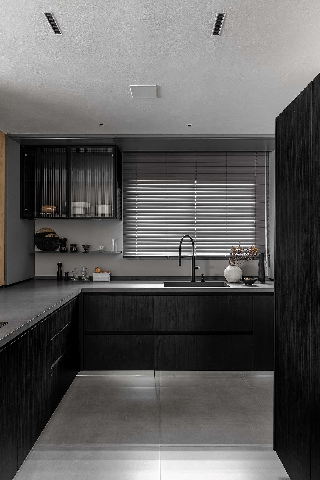 Sleek monochromatic kitchen with dark cabinetry, recessed lighting, and a window with blinds.