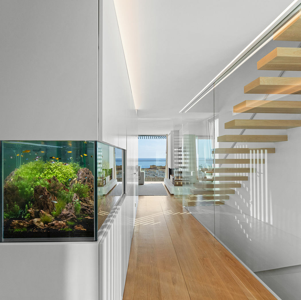 Sleek, modern interior with wooden stairs, glass walls, and an aquarium display.