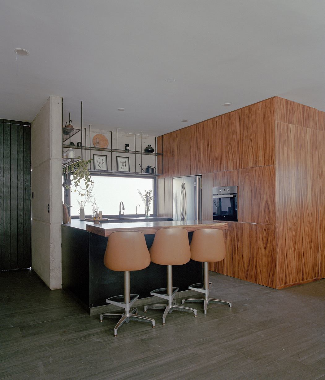 A modern kitchen with wooden cabinetry, a concrete island, and ergonomic barstools.