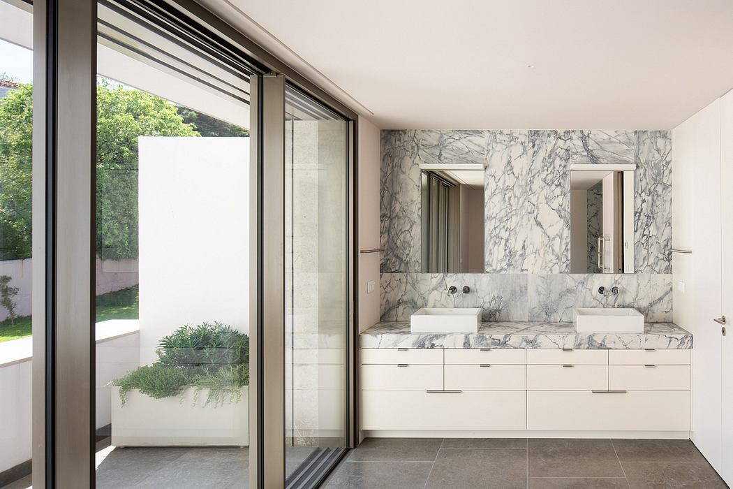 Luxurious bathroom with marble walls, double vanity, and sliding glass doors leading to garden.