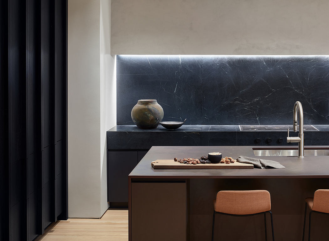 Modern kitchen with sleek black marble countertop, built-in appliances, and wooden accents.