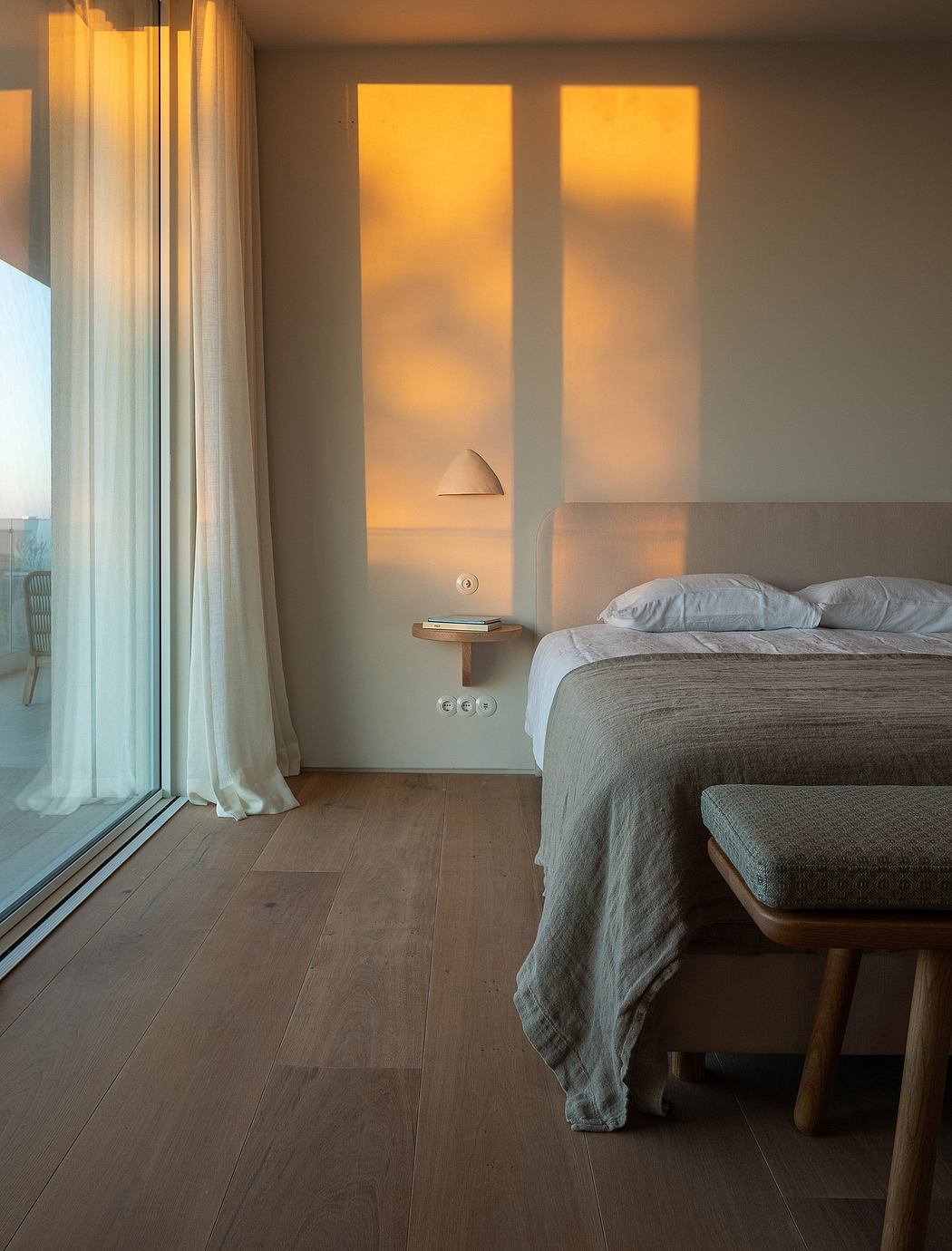 Serene bedroom with warm lighting, wood floors, and minimalist decor.