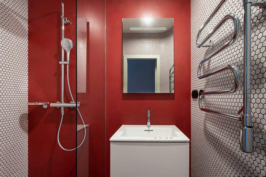 A modern, minimalist bathroom with a red accent wall and honeycomb tile pattern.