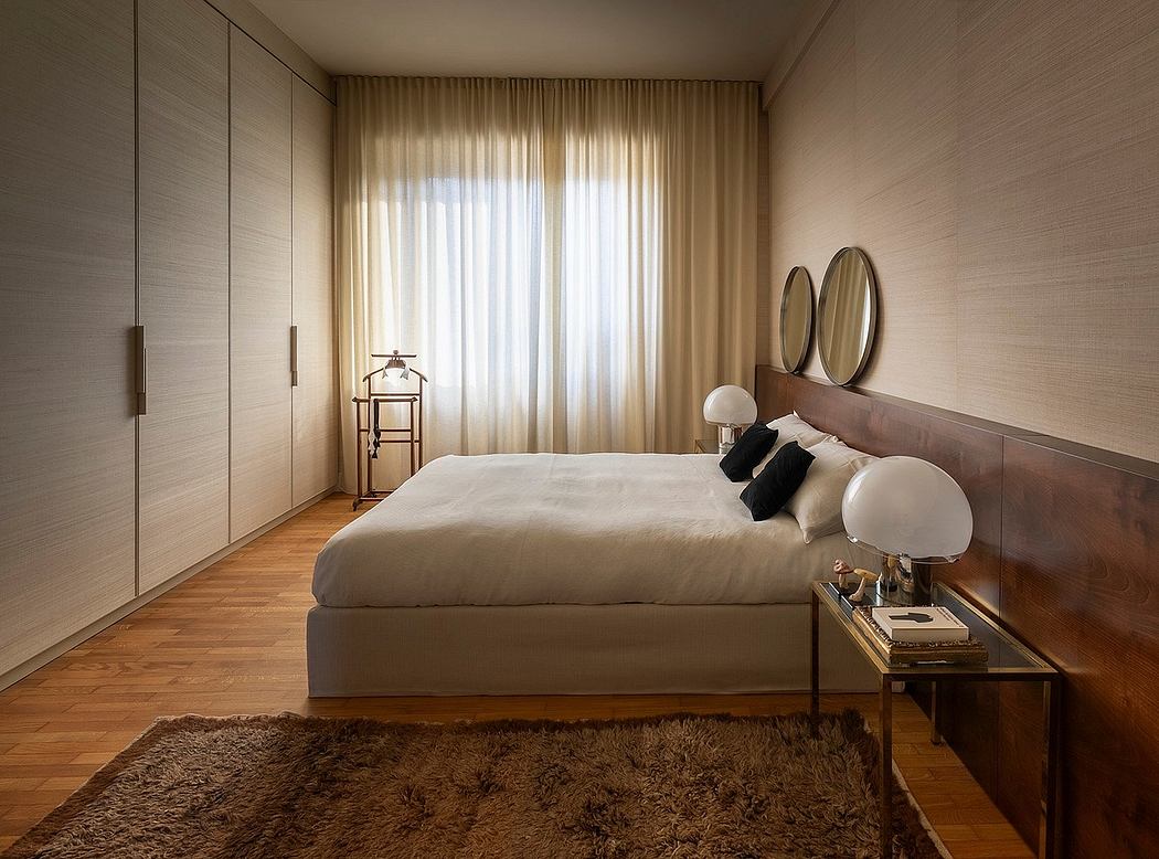 Spacious bedroom with beige curtains, wooden floors, and a plush rug. Minimalist decor.