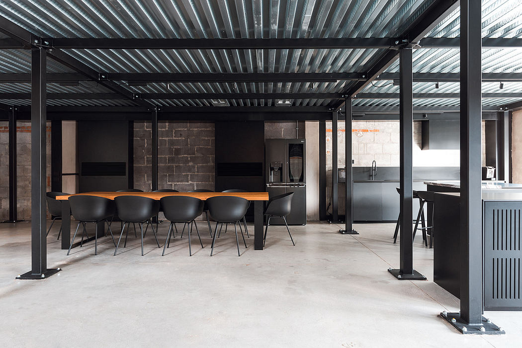 Open-concept industrial-style space with corrugated metal roof, black furniture, and concrete floor.