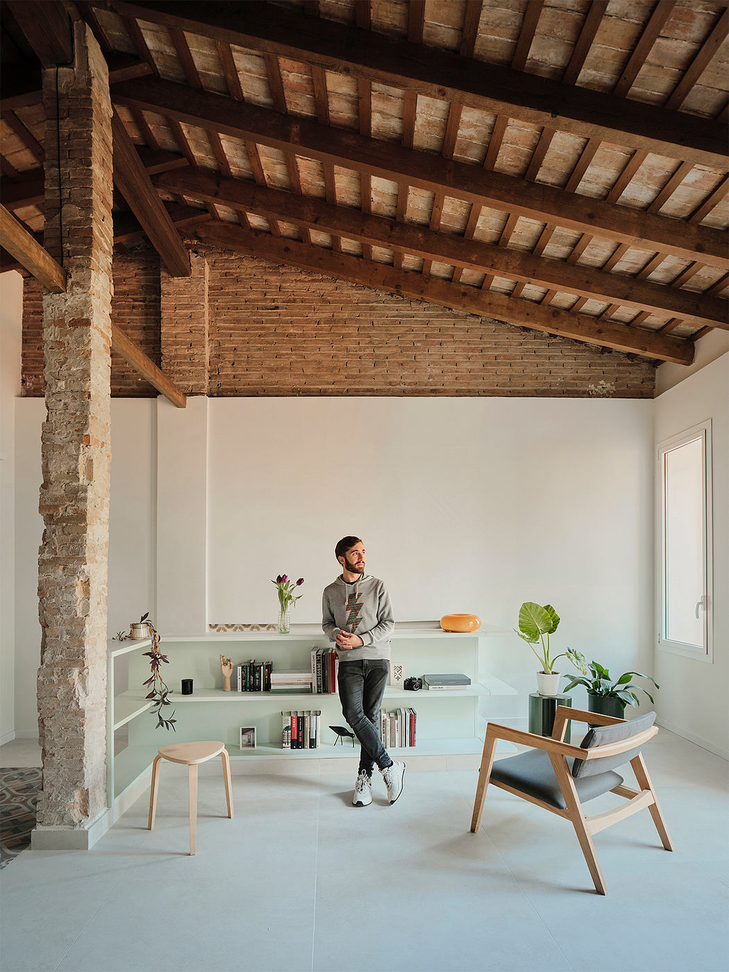 A modern, minimalist living space with exposed brick walls and wooden ceiling beams.