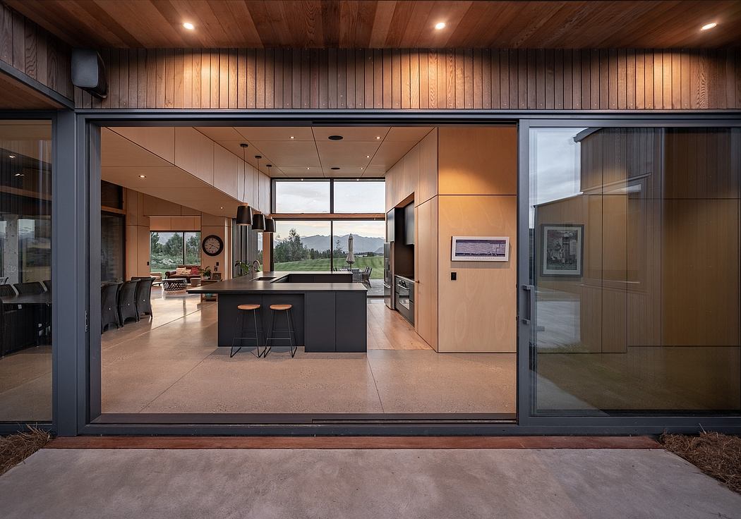 A modern, open-concept kitchen with sleek black cabinetry, a large island, and expansive windows offering scenic views.