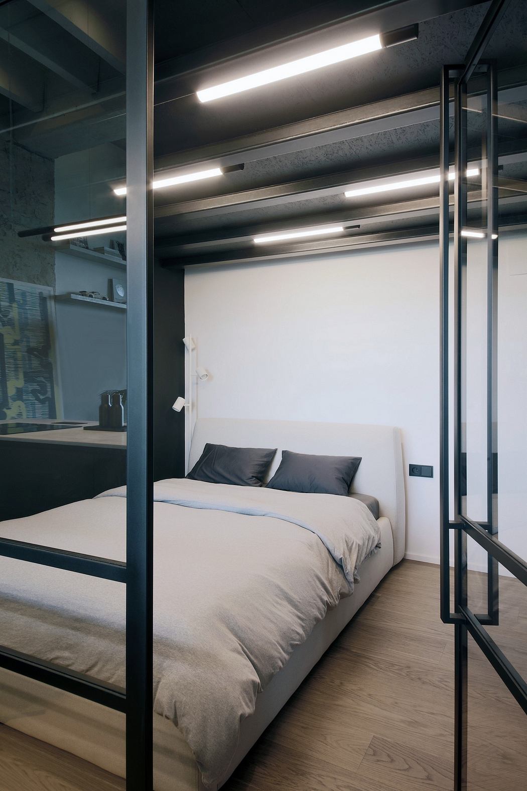 Minimalist bedroom with glass partition, recessed lighting, and wood-look flooring.