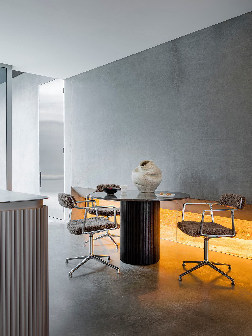 Sleek modern office design with a black circular table, cushioned chairs, and decorative accents.