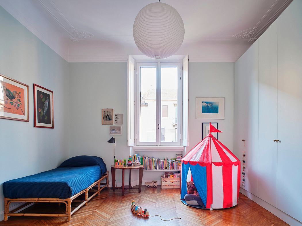 A cozy and colorful children's bedroom with a striped tent, artwork, and hardwood floors.