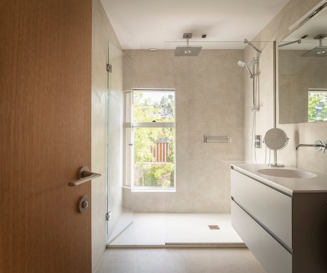 Modern, open-plan bathroom with minimalist design, large window, and sleek fixtures.