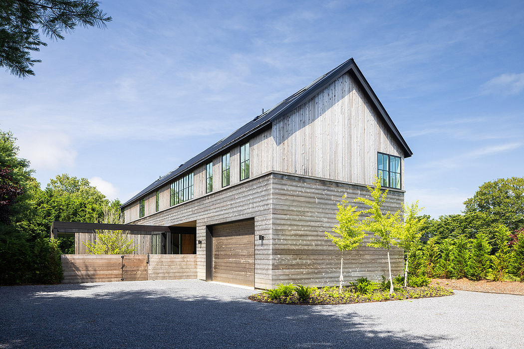 A modern, two-story wooden building with large windows and a gabled roof, surrounded by lush greenery.