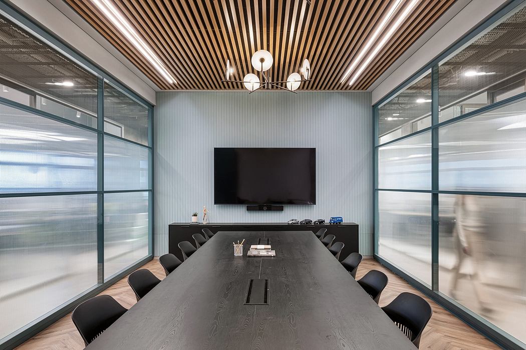 Modern office meeting room with sleek wood-paneled ceiling, large TV, and glass walls.