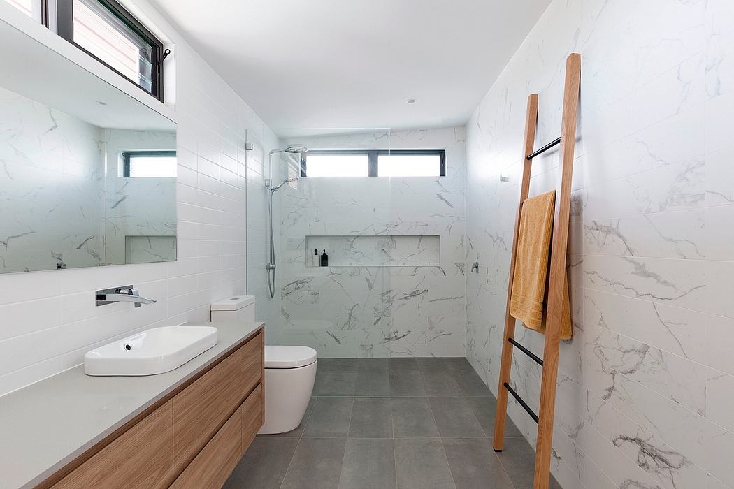A modern bathroom with a marble-tiled wall, a wooden vanity, and a minimalist design.